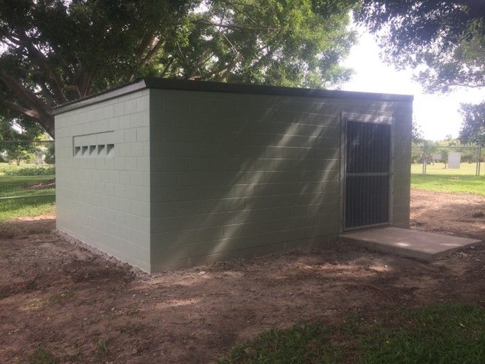 A Small White Building is Sitting in the Middle of a Grassy Field — Shedquarters In Kirwan, QLD