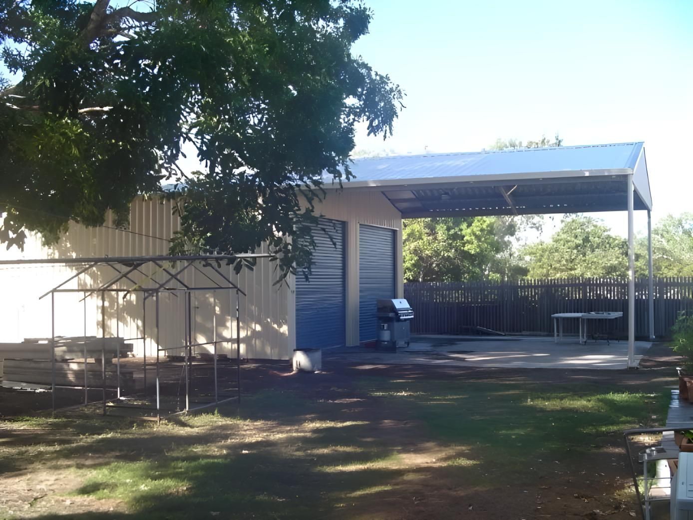 A White Building With A Blue Door And A Canopy Over It — Shedquarters In Kirwan, QLD