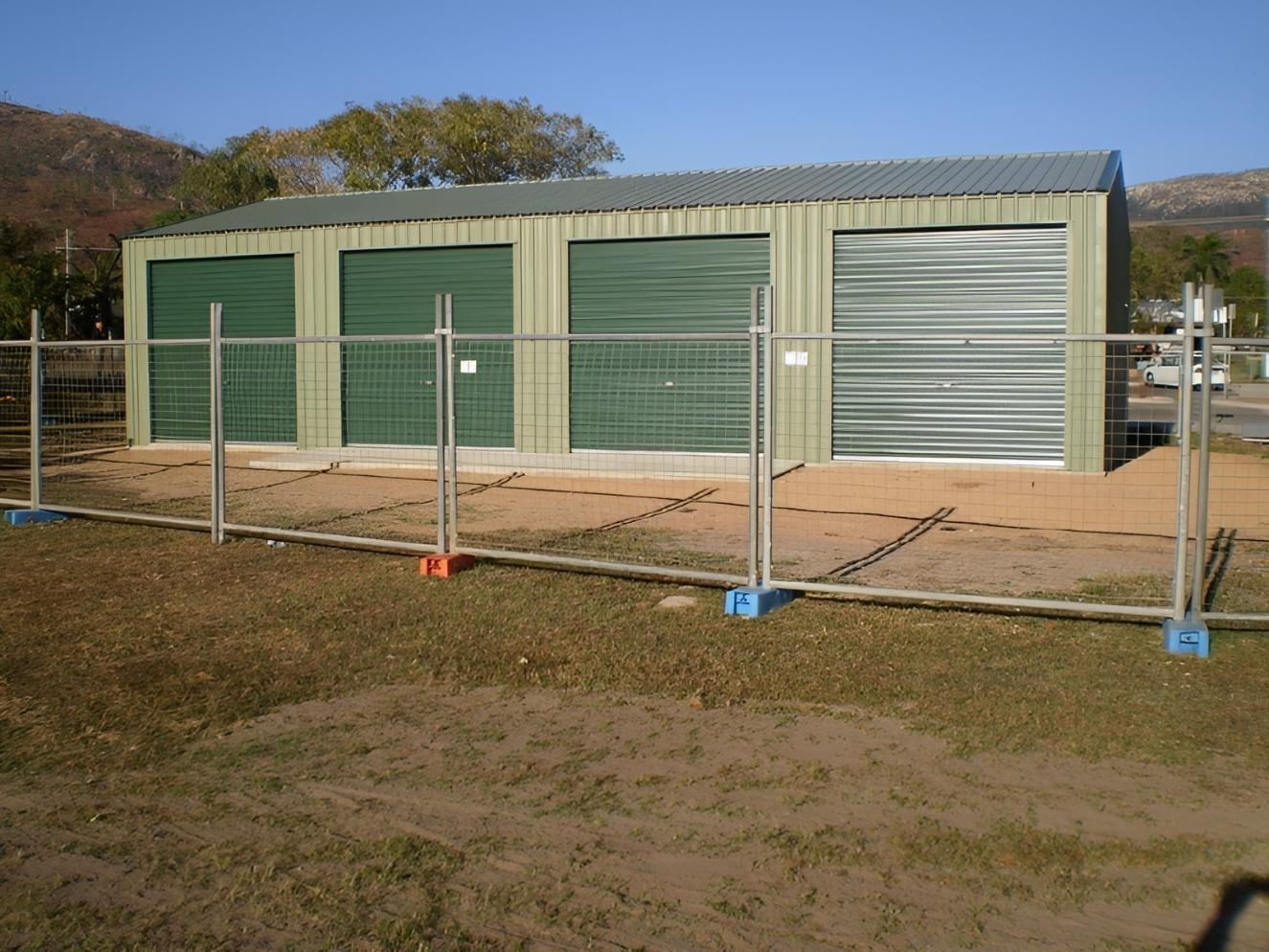 A Fence Surrounds A Building With Green Doors — Shedquarters In Kirwan, QLD