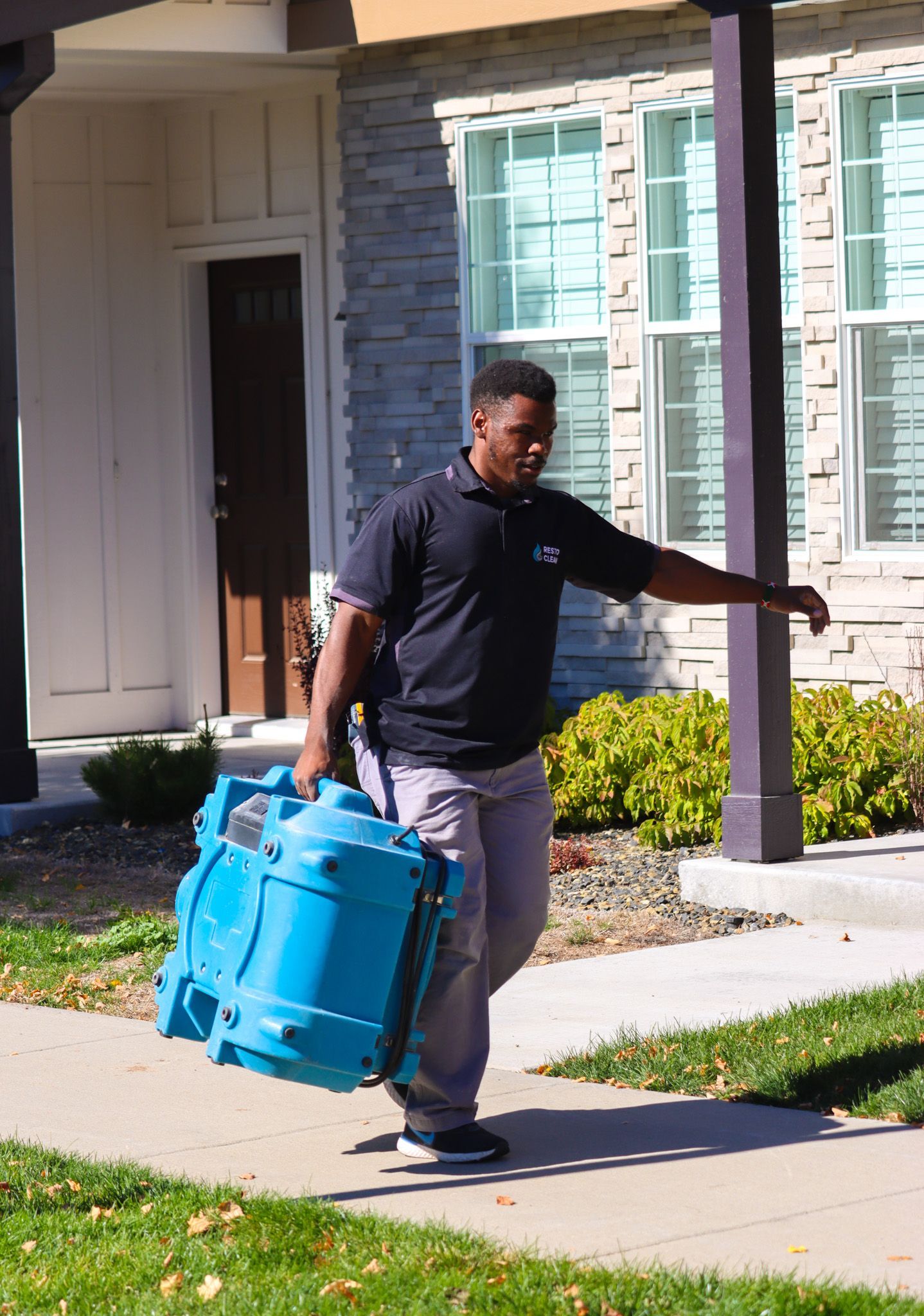 a man is walking down the sidewalk carrying a blue bag .