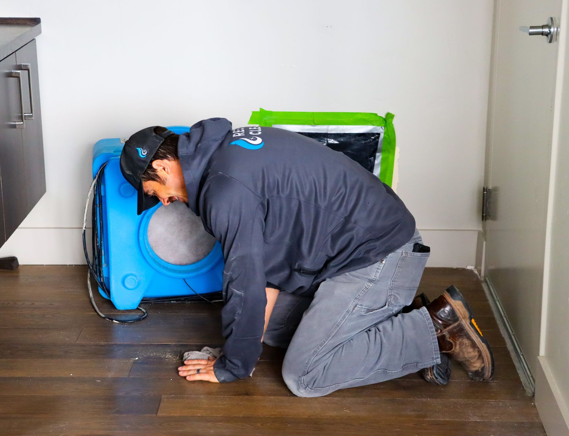 A man is kneeling on the floor next to a machine.