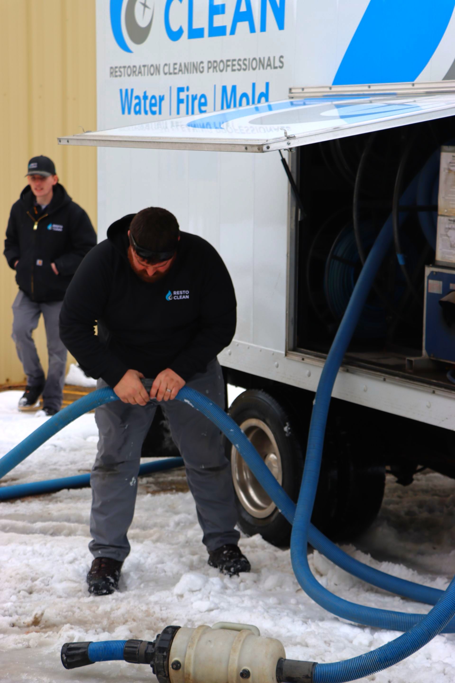 A man is working on a hose in front of a clean truck