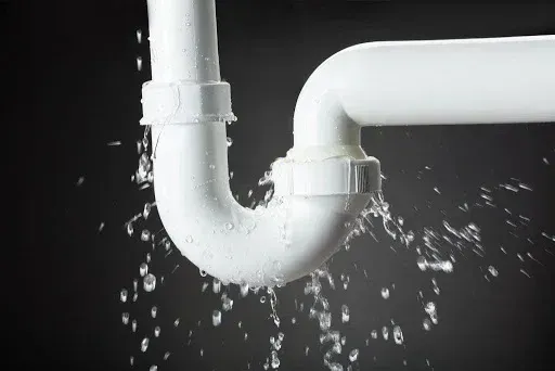 A white pipe is leaking water on a black background.