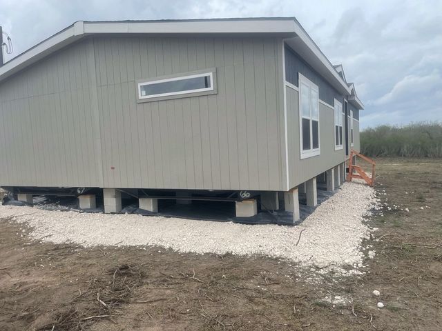 A mobile home is sitting on stilts in a field.