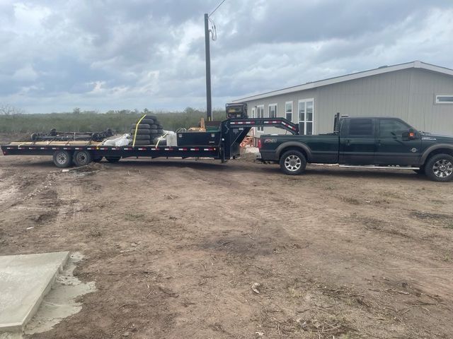 A truck with a trailer attached to it is parked in front of a house.