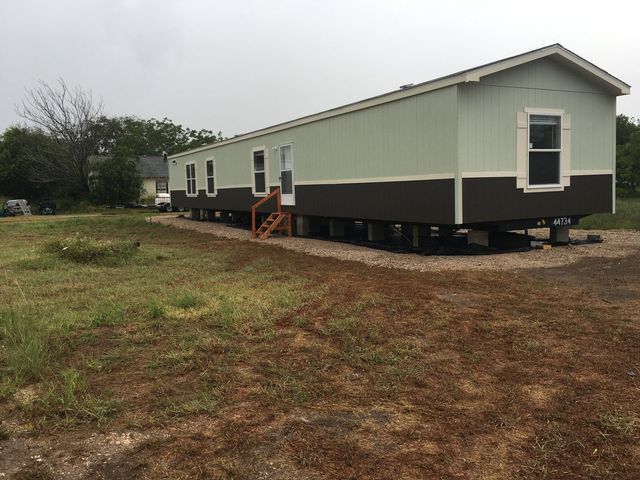 A mobile home is sitting in the middle of a grassy field.