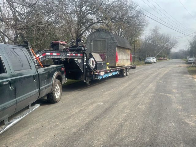A truck is towing a trailer with a shed on it.