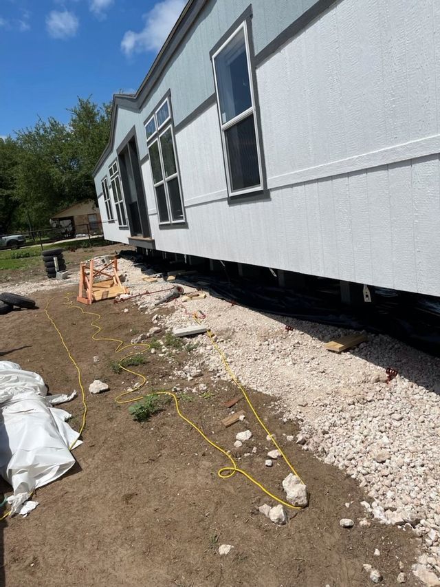 A mobile home is being built in a dirt field.