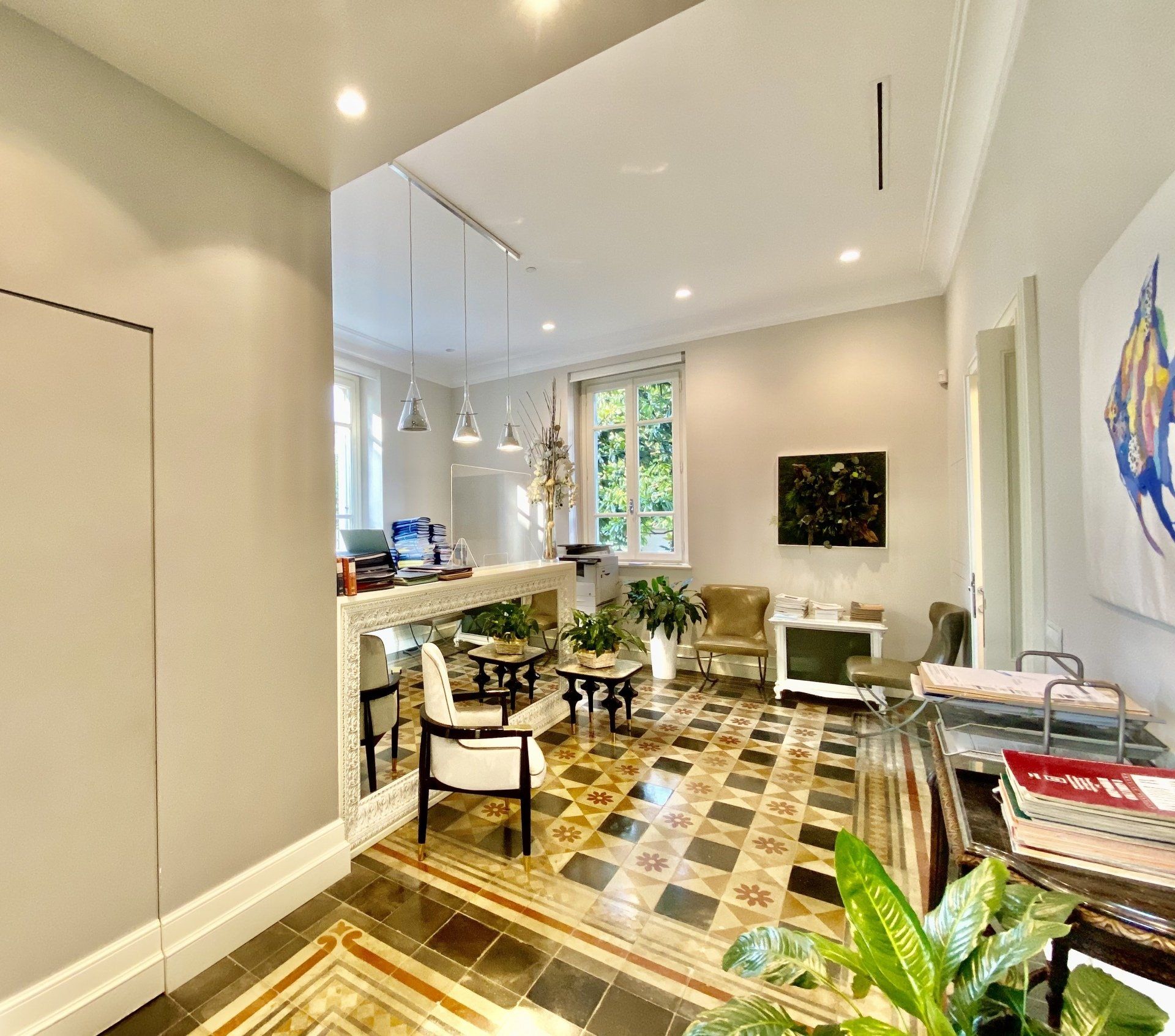 Area reception con pavimento decorato, piante, opere d'arte e posti a sedere.