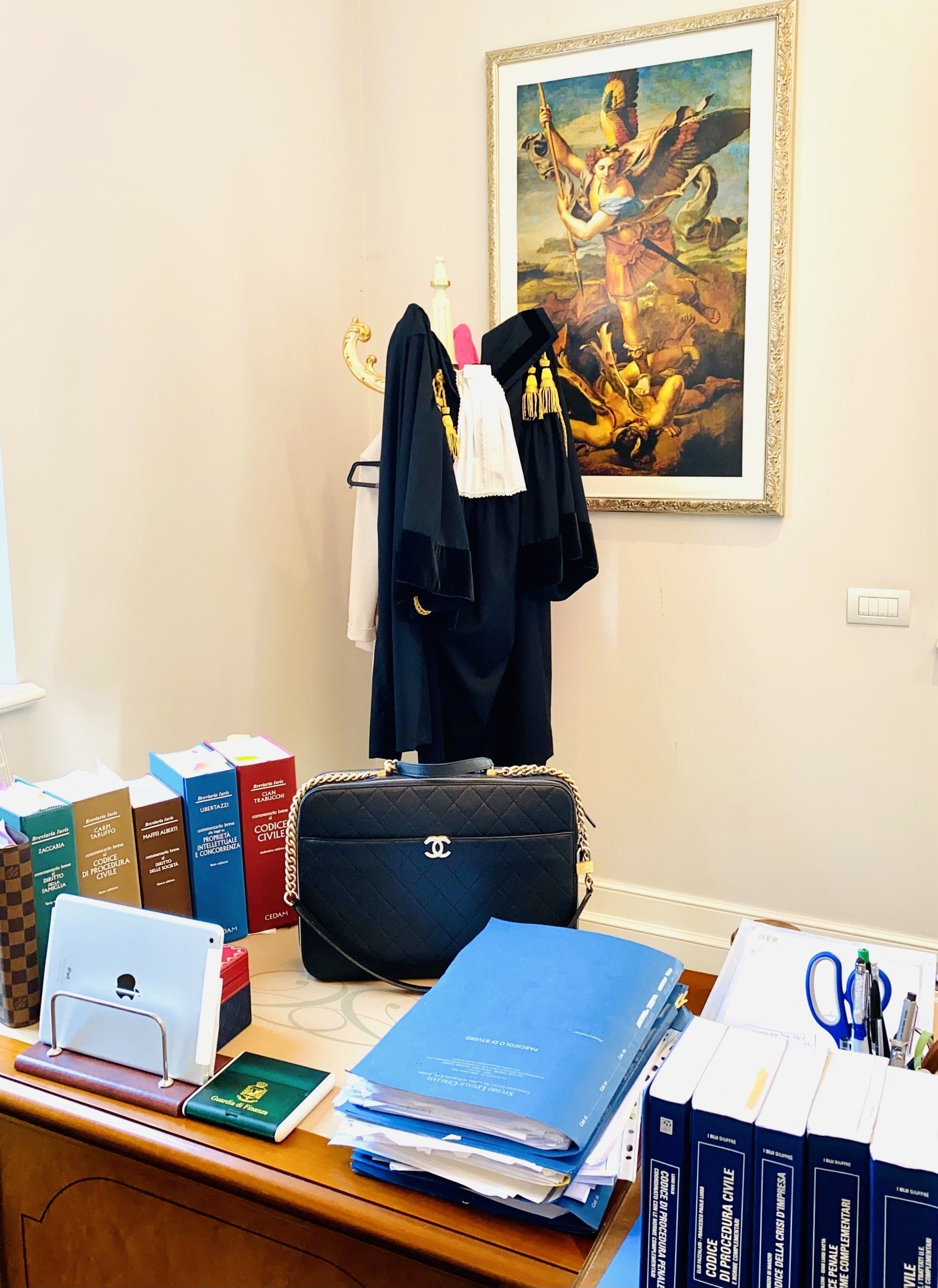 Studio legale con toghe, libri e documenti. Un quadro appeso alla parete.