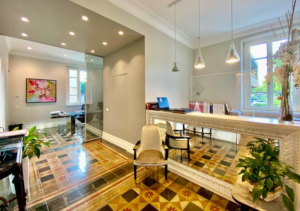 Elegante area reception con pavimento decorato, scrivania a specchio e opere d'arte moderna.