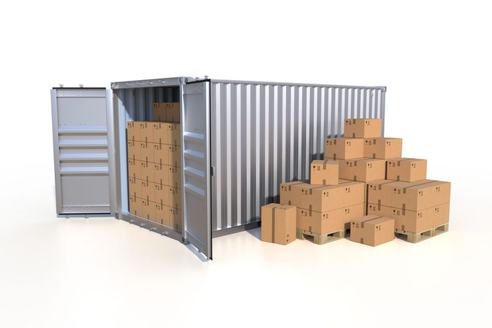 Shipping container with open doors, partially filled with cardboard boxes, and a pile of boxes outside.