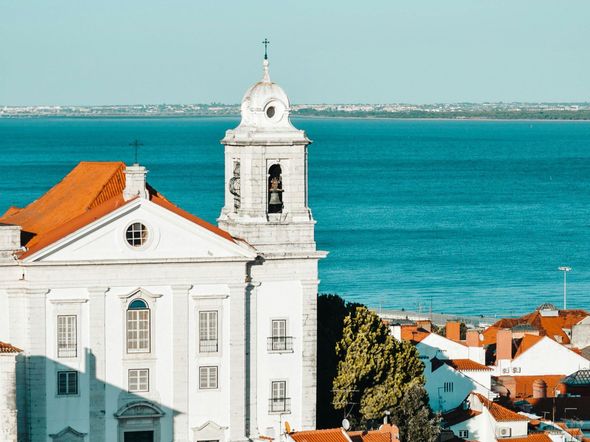 A white building with a clock tower in front of a body of water.