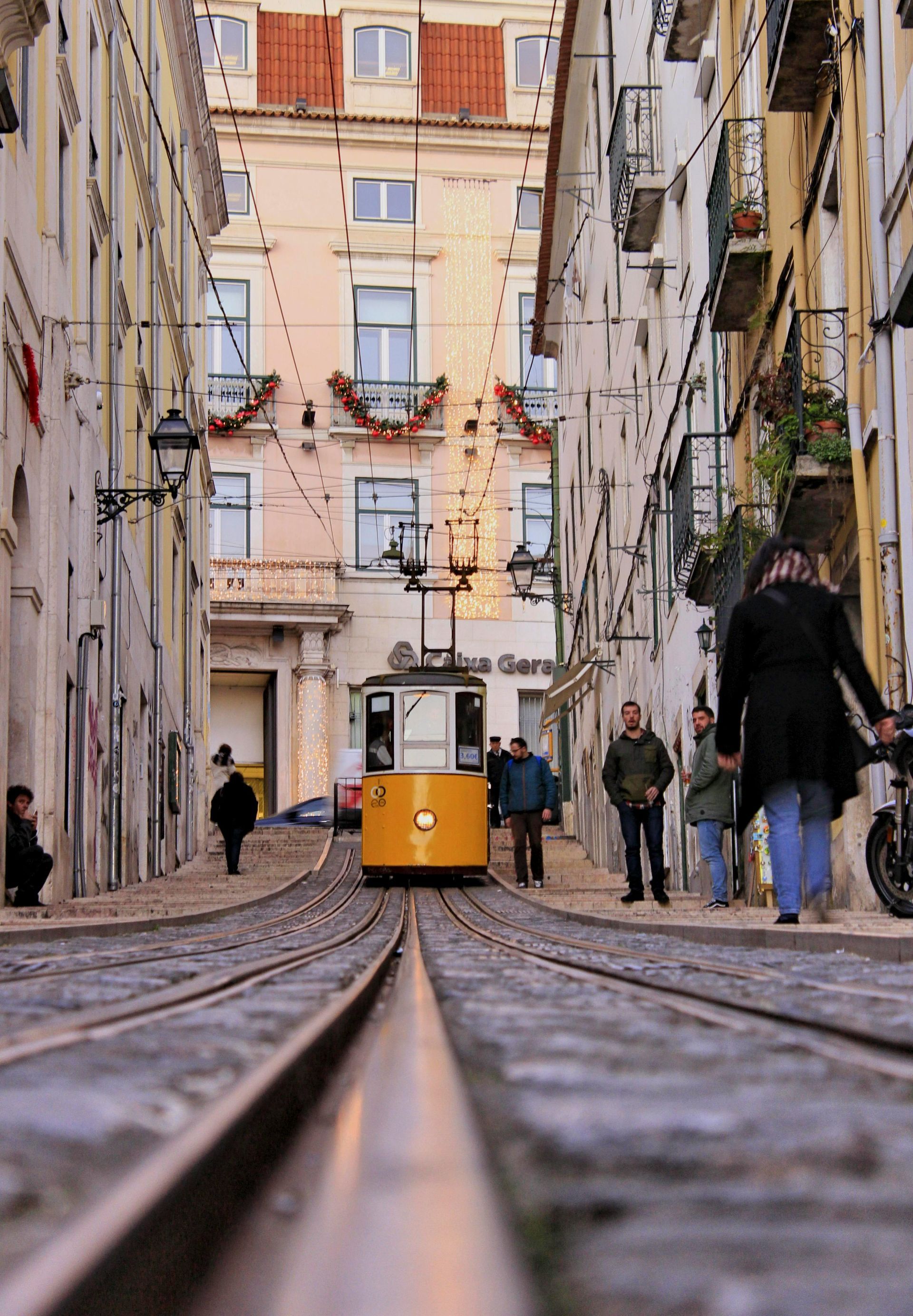 A yellow trolley is going down a narrow street
