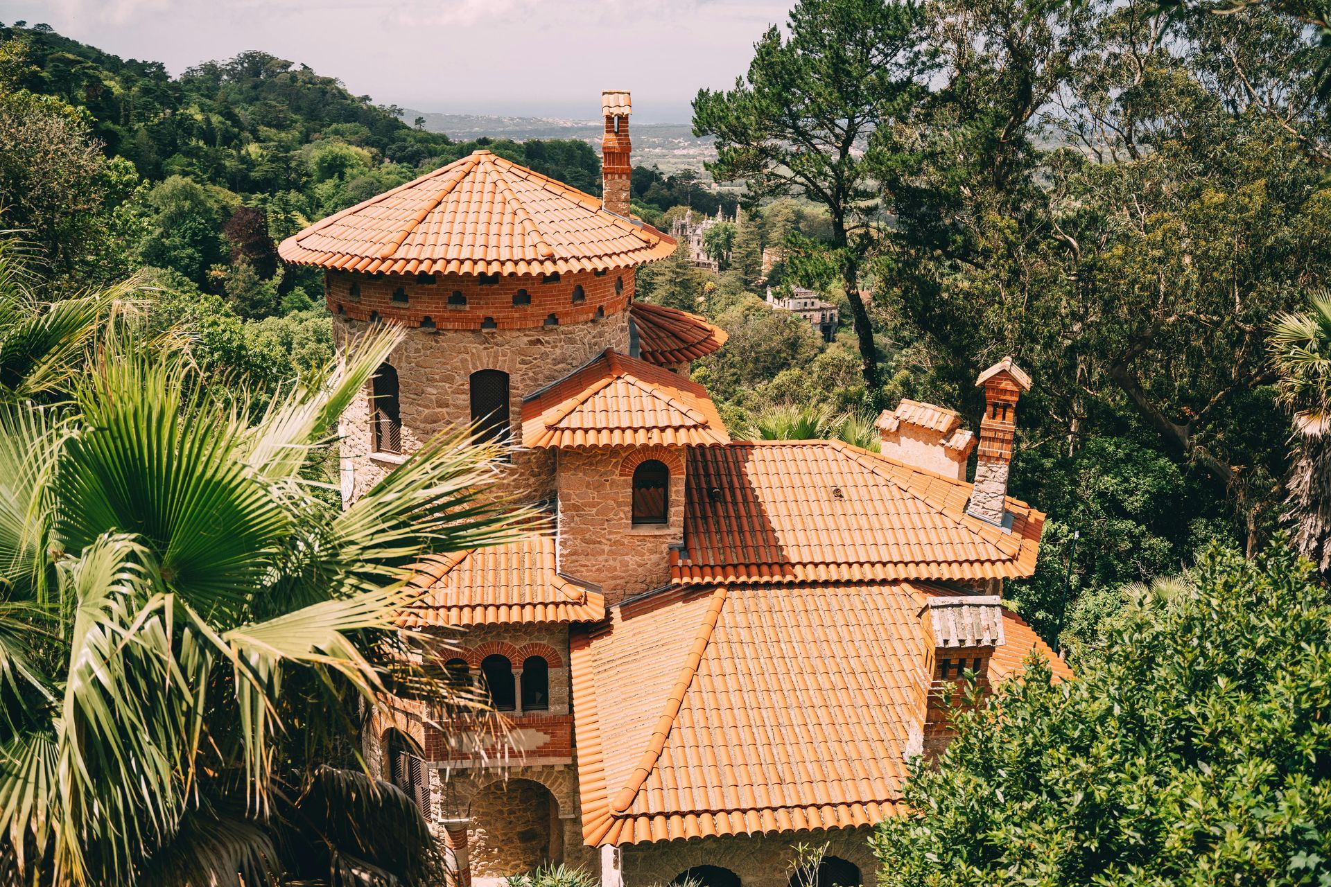 A large house with a tiled roof is surrounded by trees.