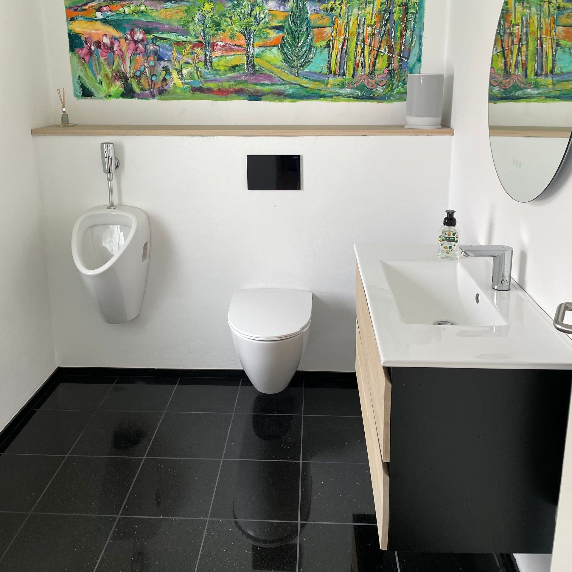 Et badeværelse med toilet, urinal og håndvask