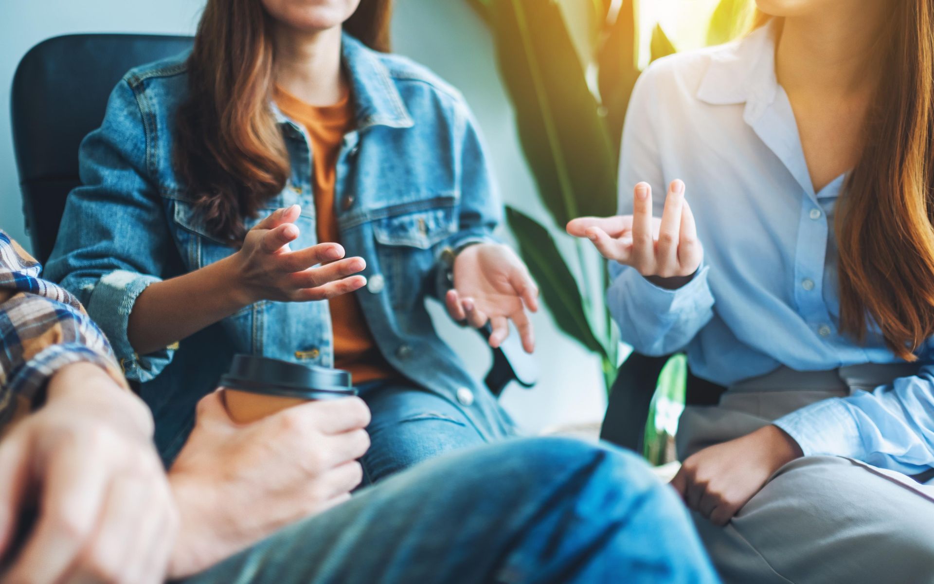 Group of people in casual clothing talking in a room with natural light.