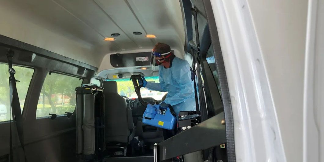 A man is cleaning the inside of a bus with a vacuum cleaner.