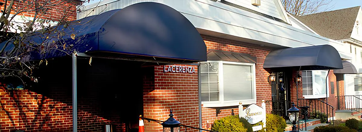 A brick house with a blue awning over the front door