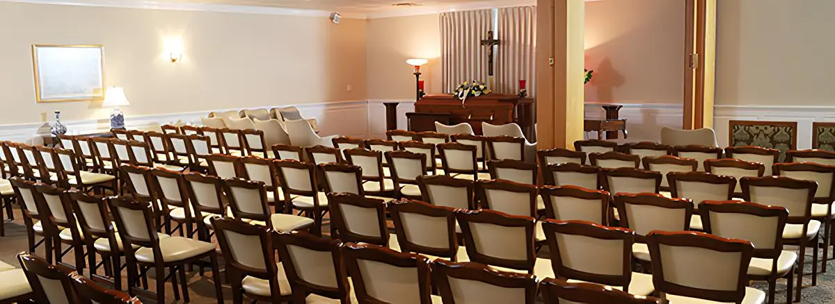 A large room filled with rows of chairs and a cross on the wall.