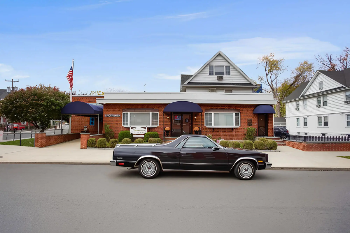 A black car is parked in front of a funeral home.