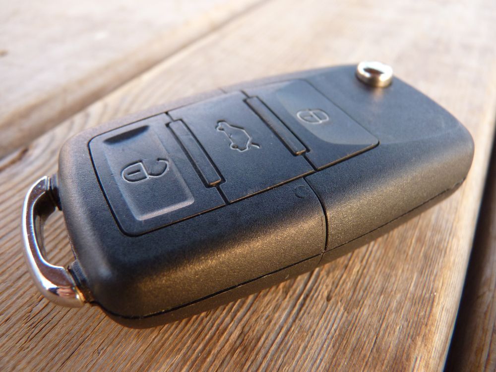 Black Car Key Fob With Three Buttons on a Wooden Surface — Battery Assist Brisbane in Aspley, QLD