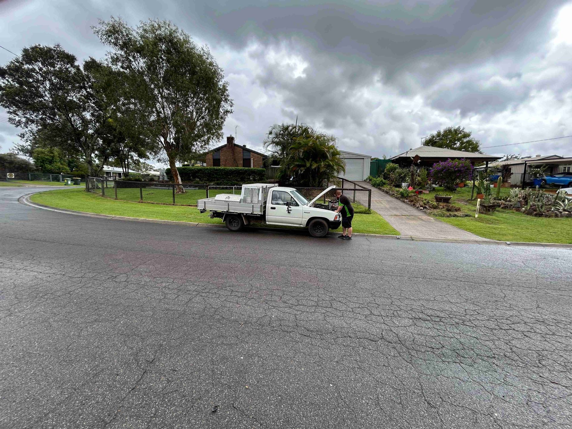 White pickup truck with hood open on a residential street; person working on the engine — Battery Assist Brisbane in Caboolture, QLD