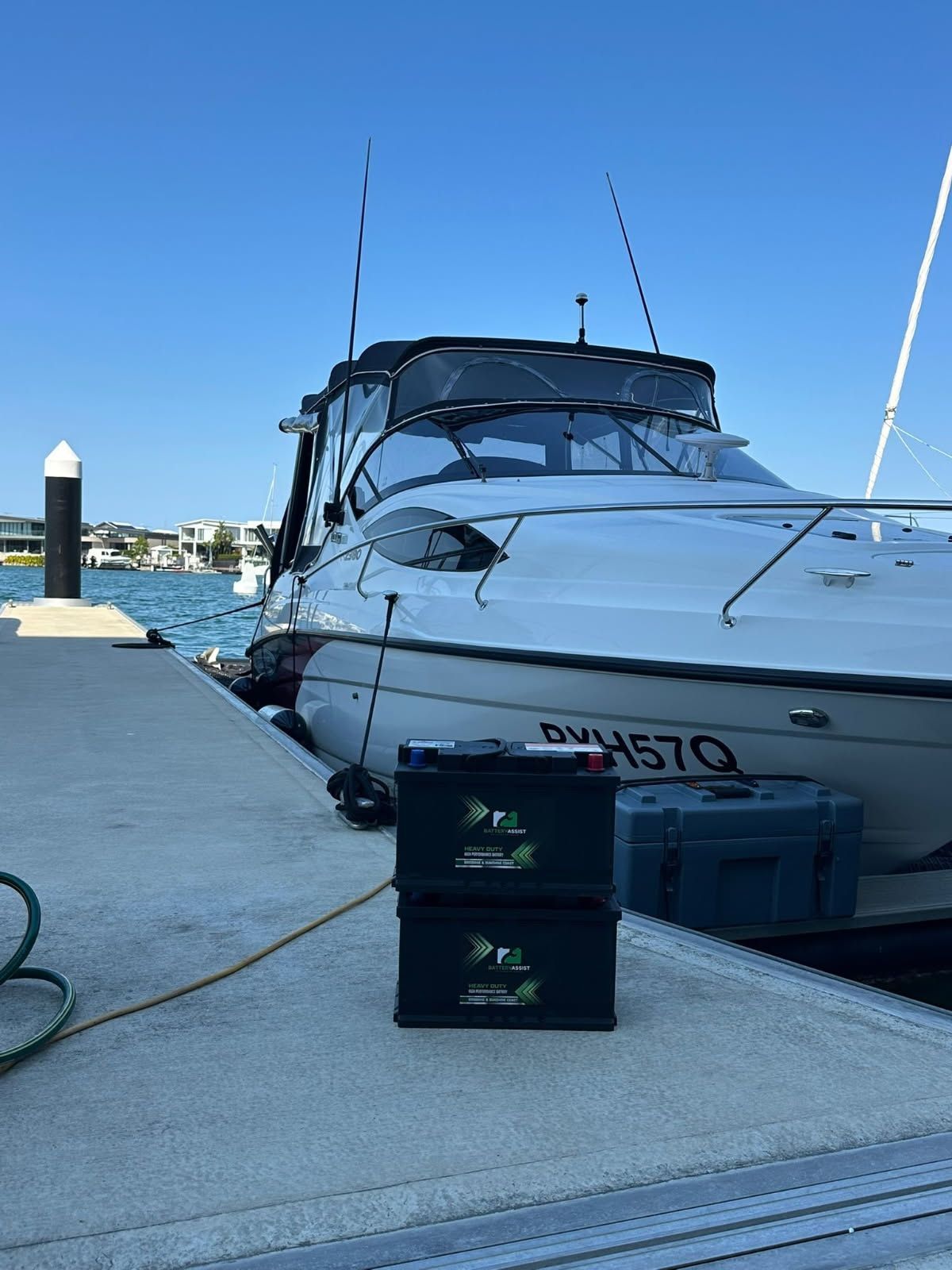 Two black containers stacked on a concrete dock, a boat is docked next to it on a sunny — Battery Assist Brisbane in Caboolture, QLD