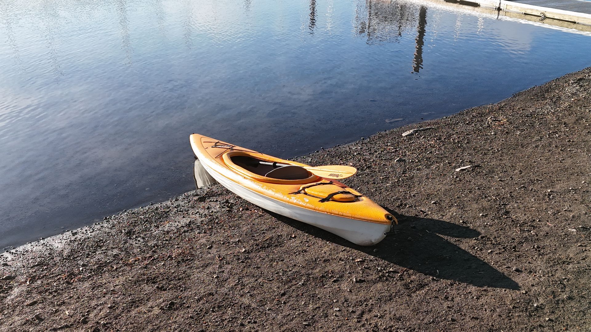A woman is paddling a yellow kayak on a lake.