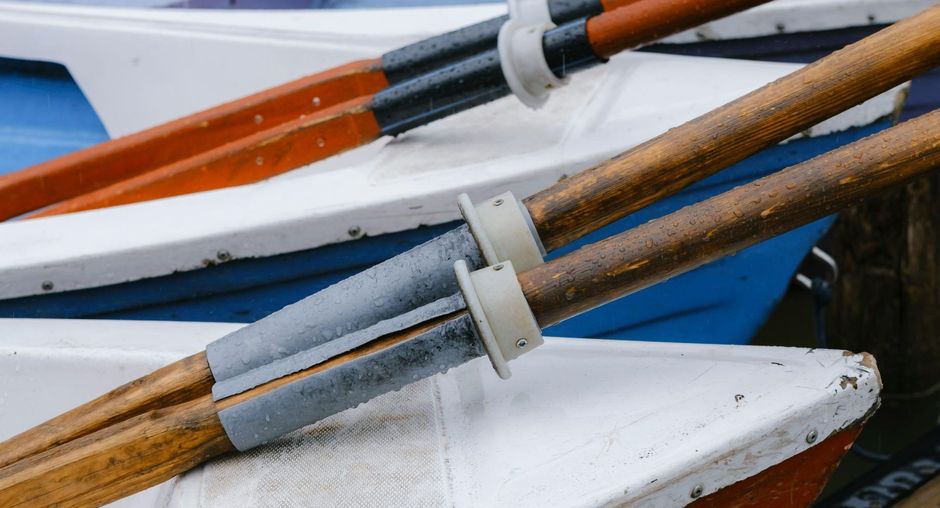 Three wooden oars are stacked on top of each other on a boat.