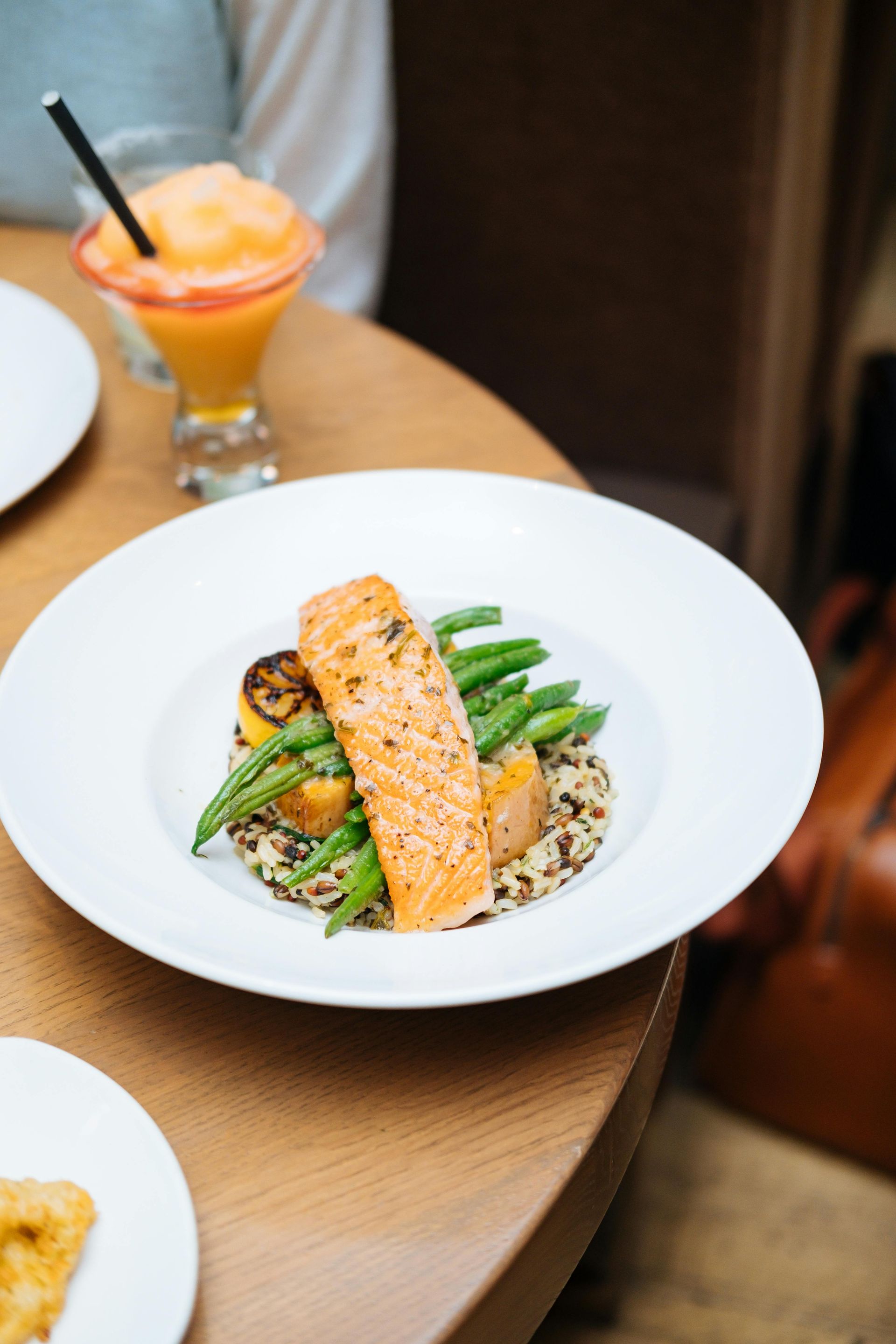 A plate of food with a drink in the background on a table.