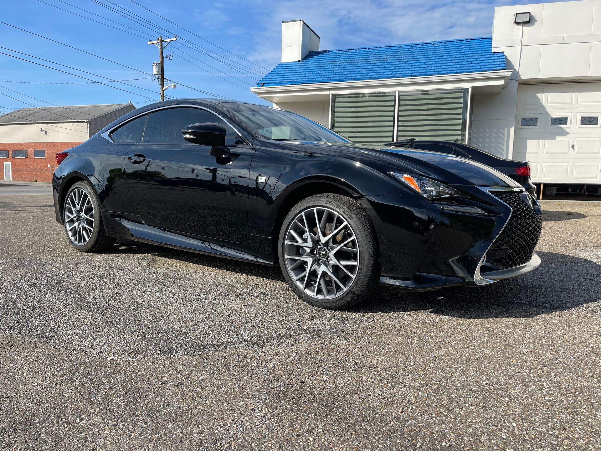 A black lexus rc is parked in front of a building.