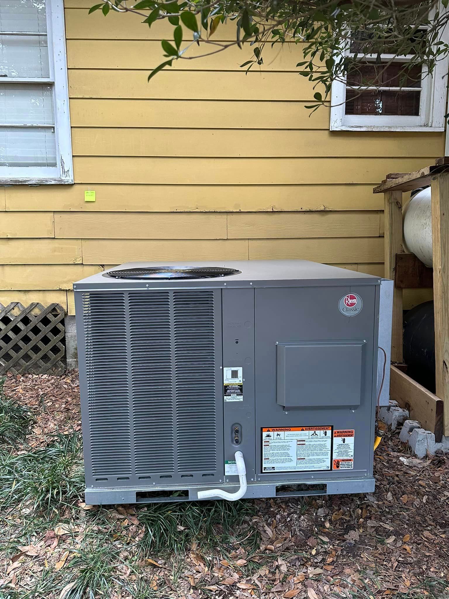 A white air conditioner is hanging on a white wall next to a window.
