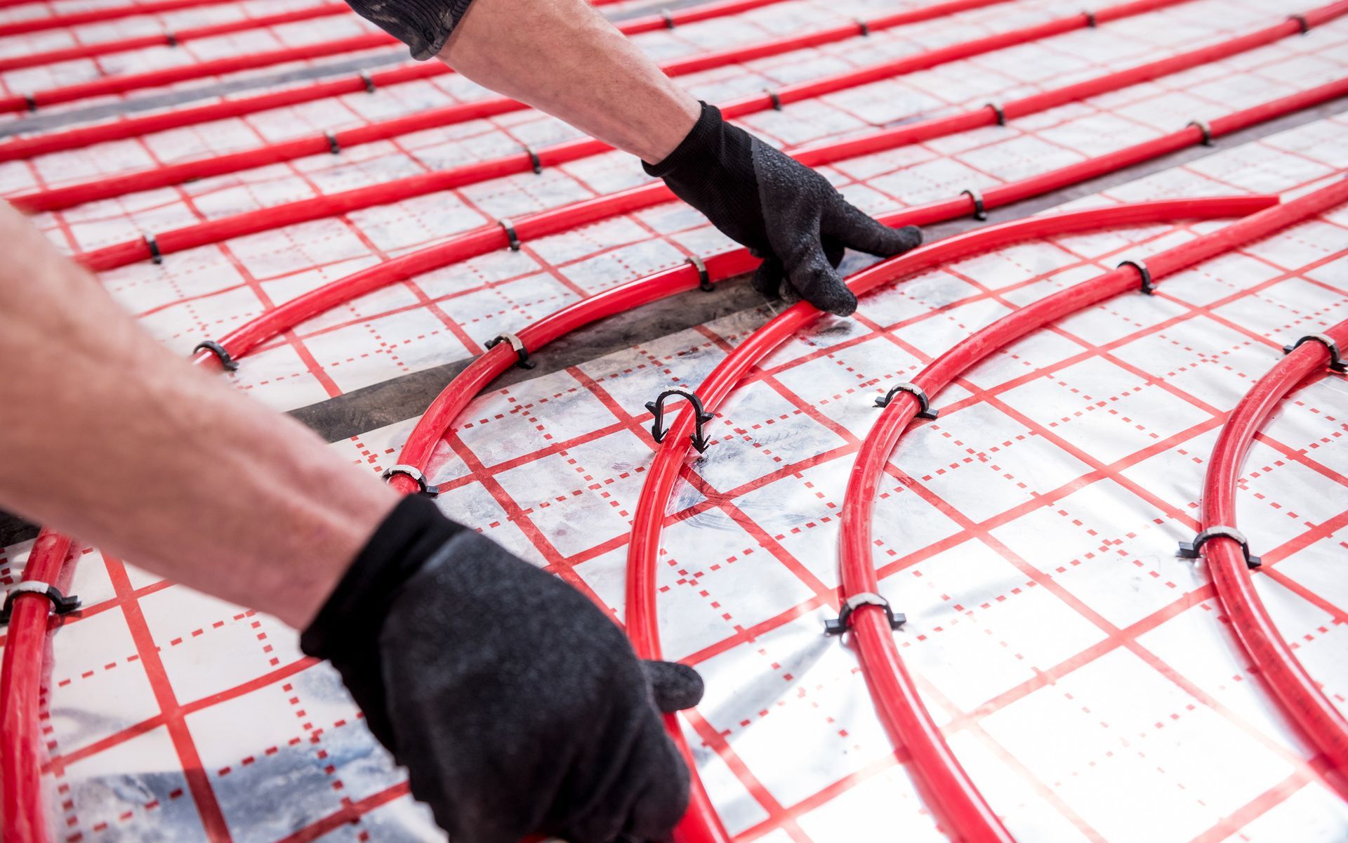 A man is installing underfloor heating in a room.