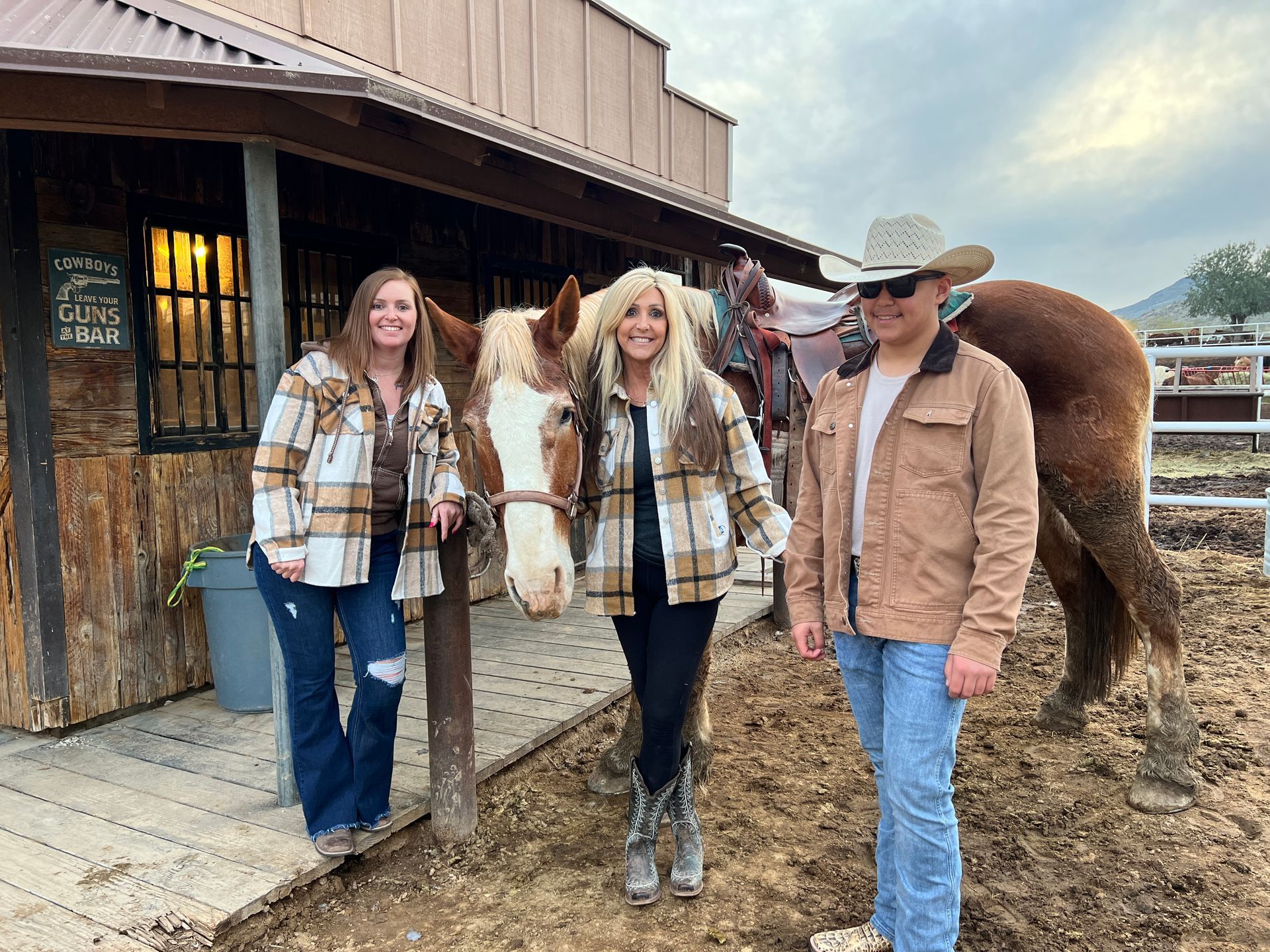 A man and two women are standing next to a horse in a stable.
