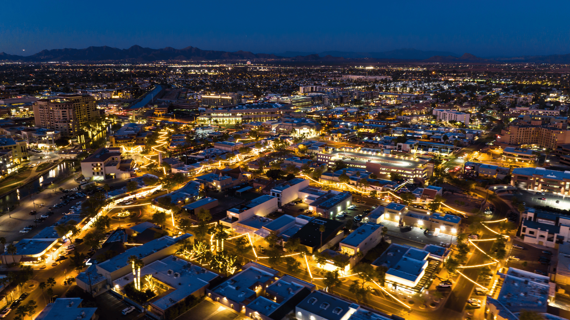 An aerial view of a city at night with lots of lights on the buildings.