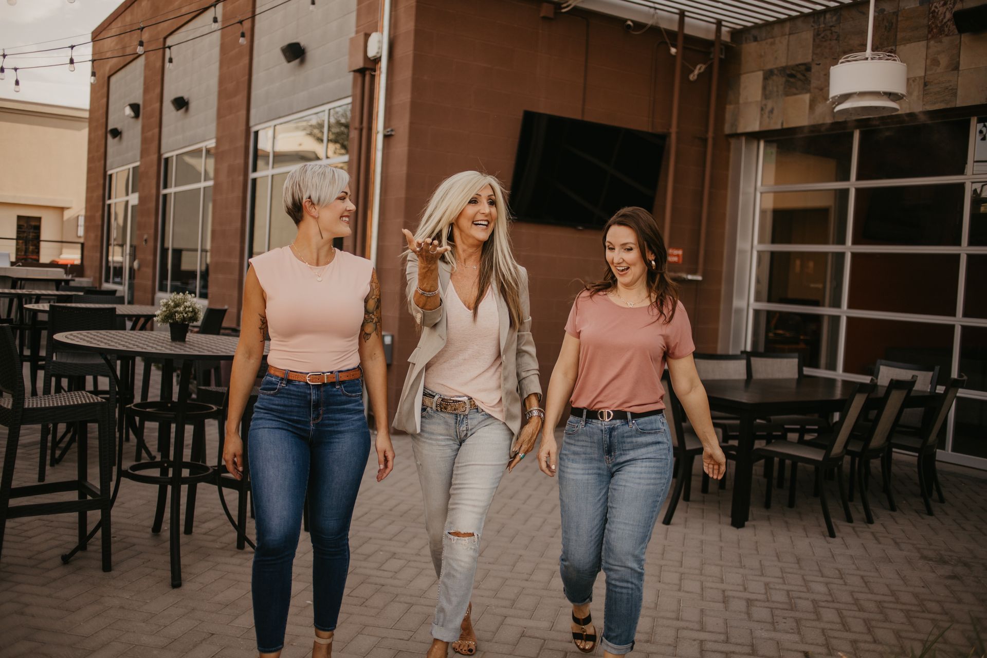 Three women are walking down a sidewalk in front of a building.