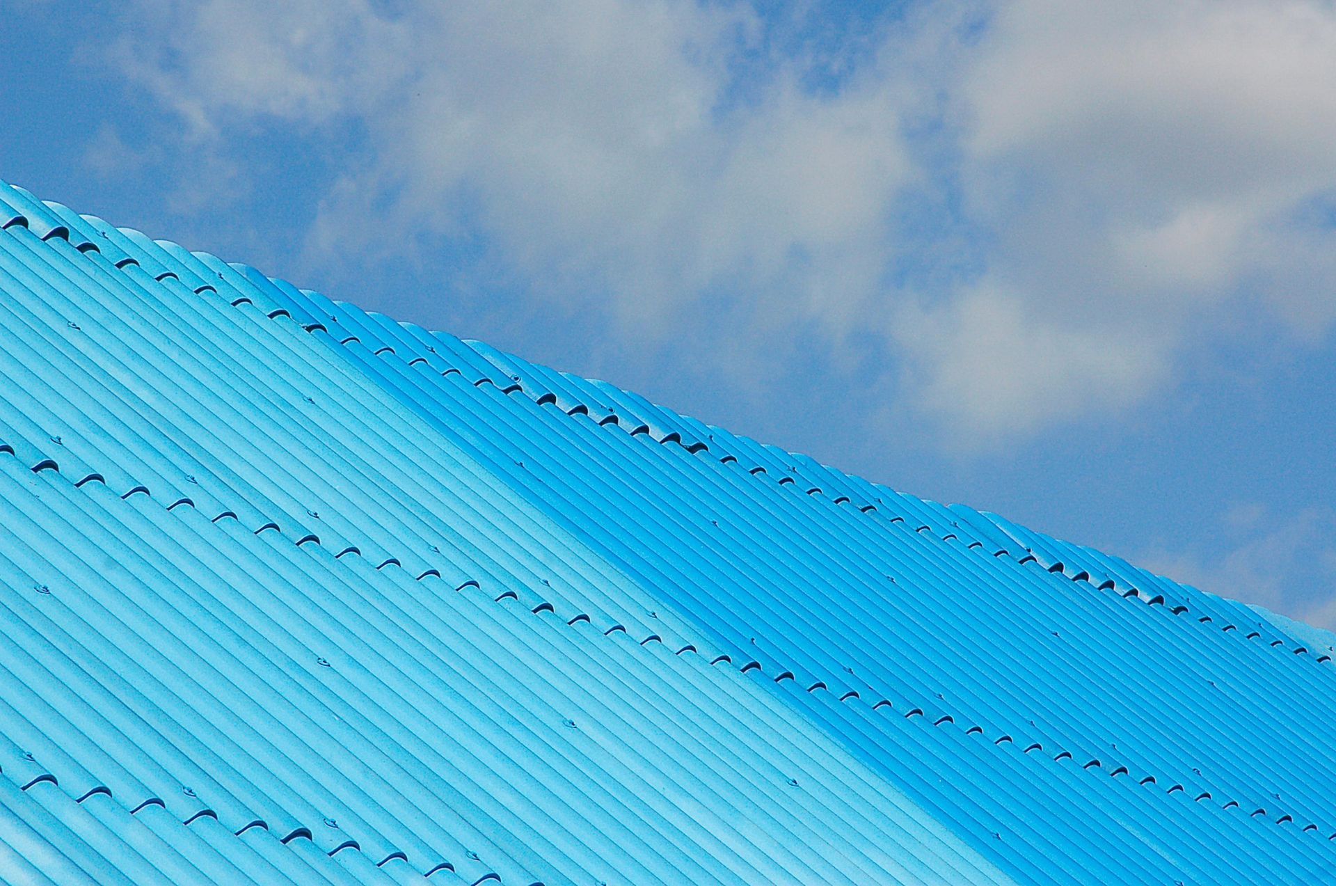 Blue corrugated metal roof against a cloudy sky