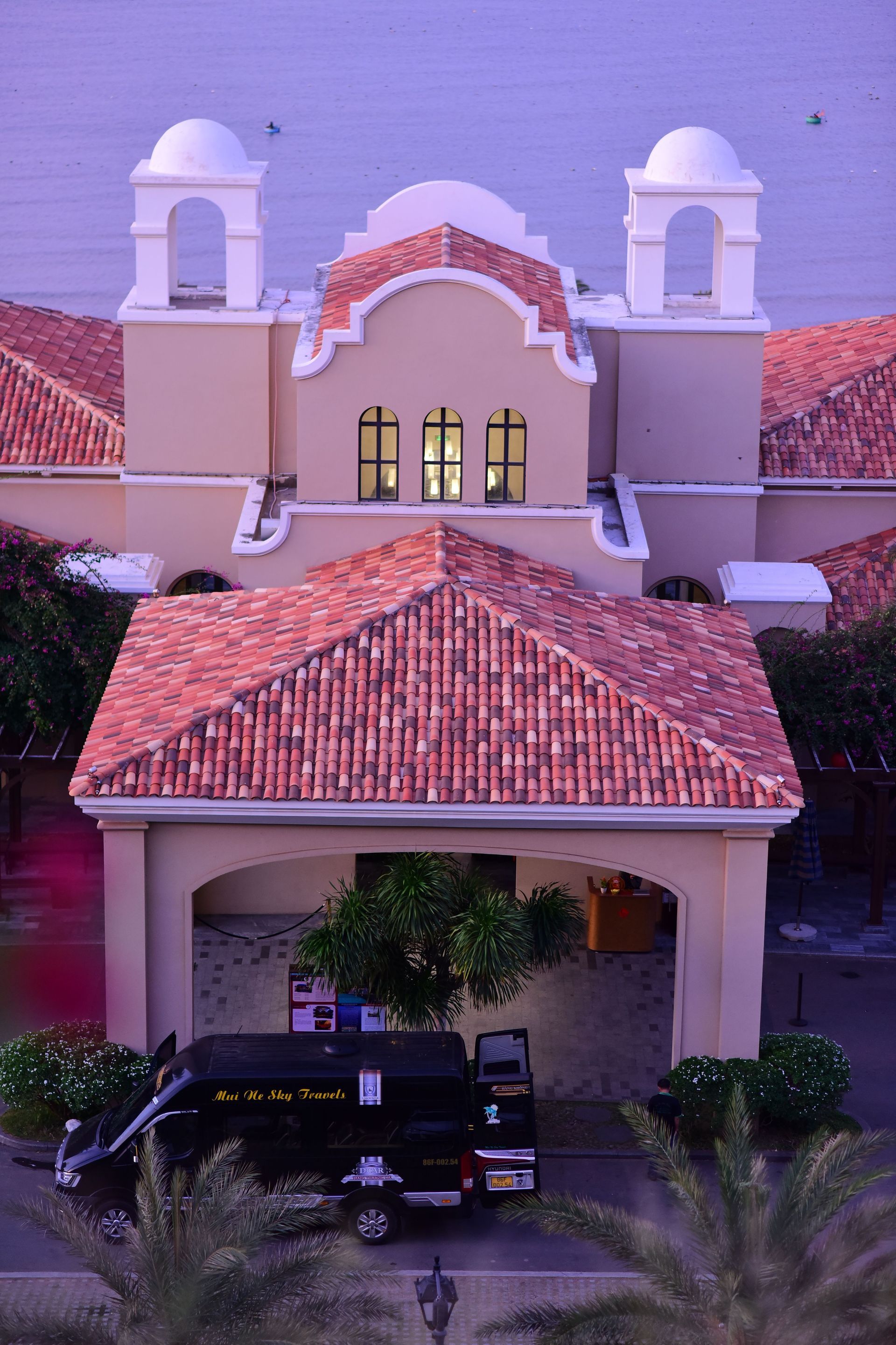 Spanish-style house with red tile roofs, arched entry, and two white towers