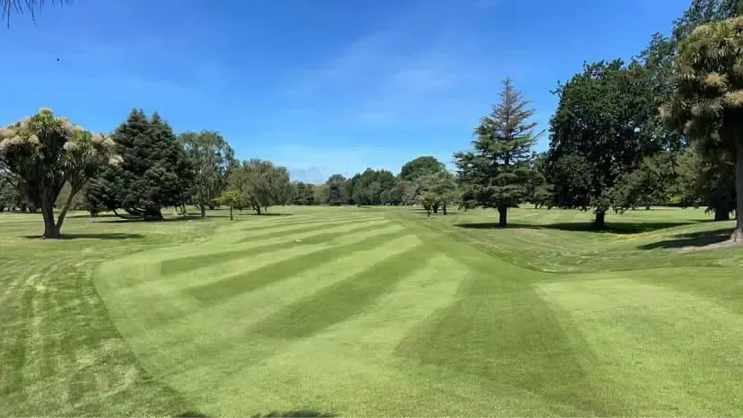 A golf course with trees and grass on a sunny day.