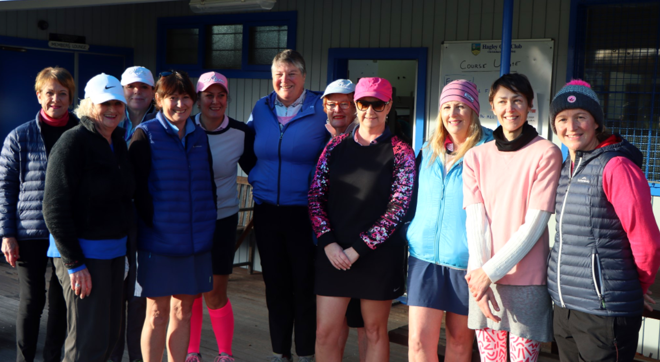 A group of women are posing for a picture in front of a building.