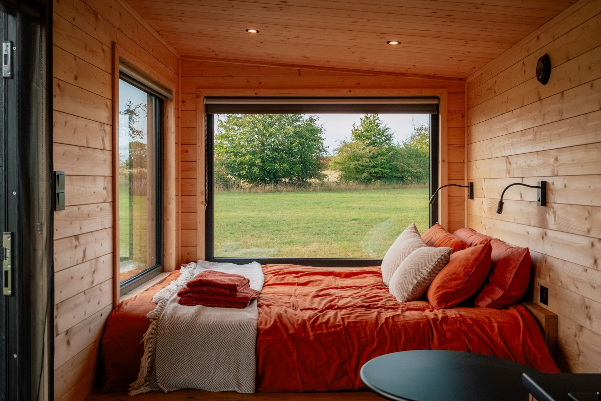 View from cabin bed to wildflower meadow through large window.