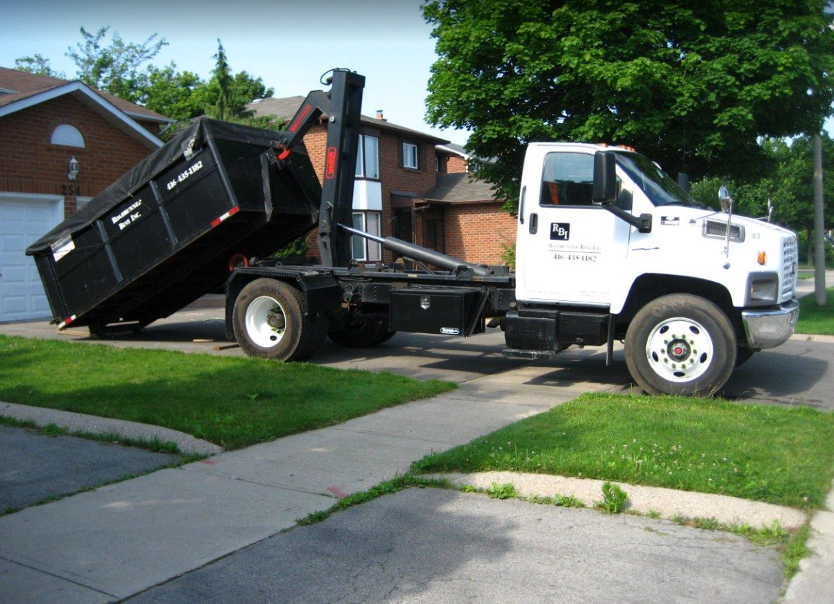 a dumpster truck is parked in front of a brick house