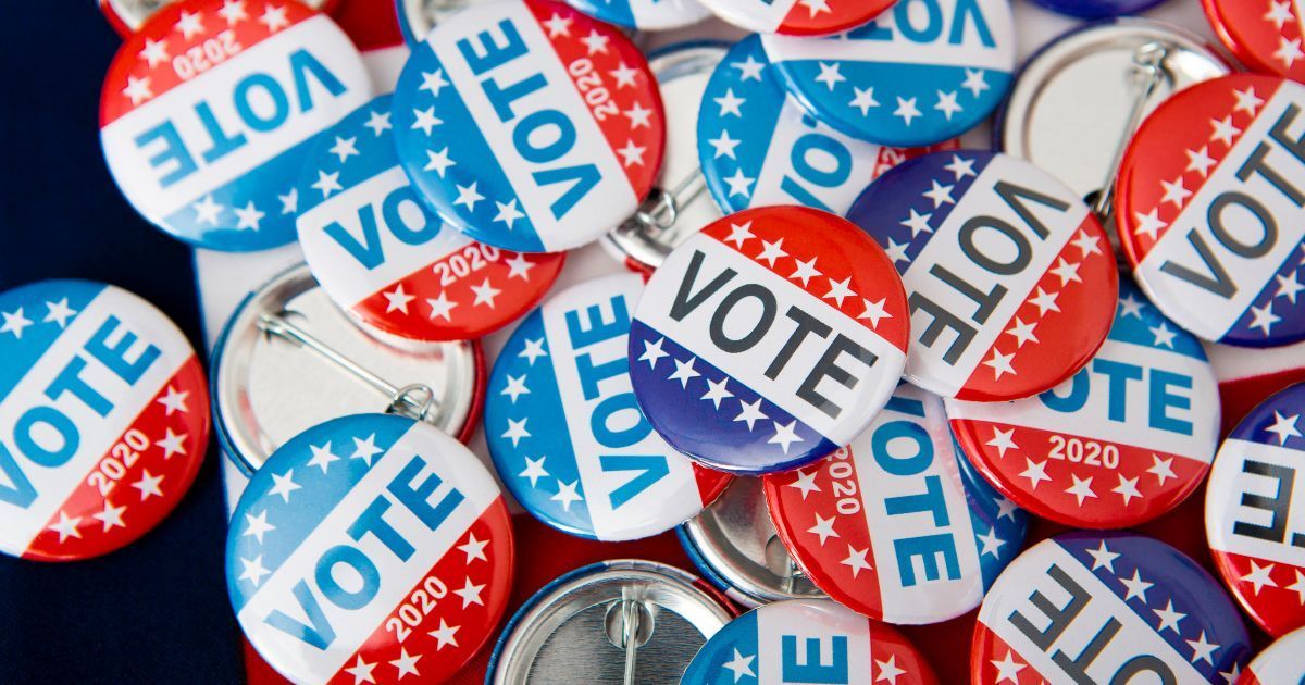 A pile of red , white and blue vote buttons on a table.