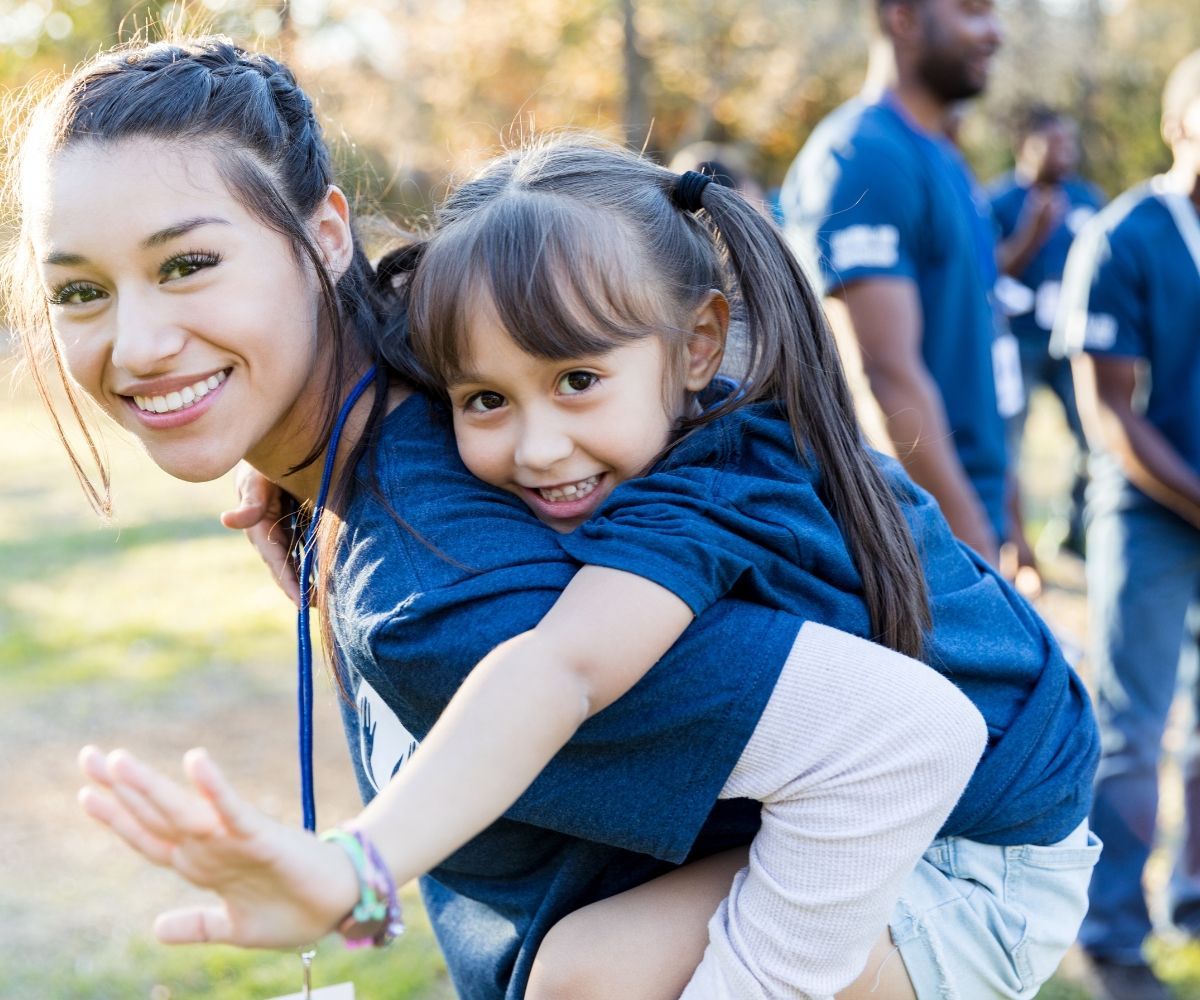 A woman is carrying a little girl on her back.