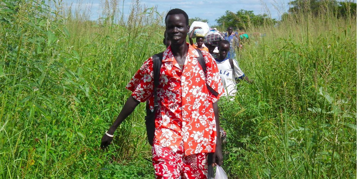 A group of people are walking through a grassy field.