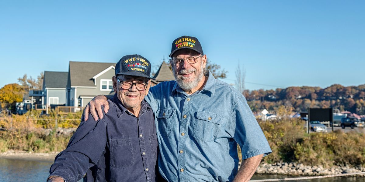 Two men are standing next to each other in front of a house.