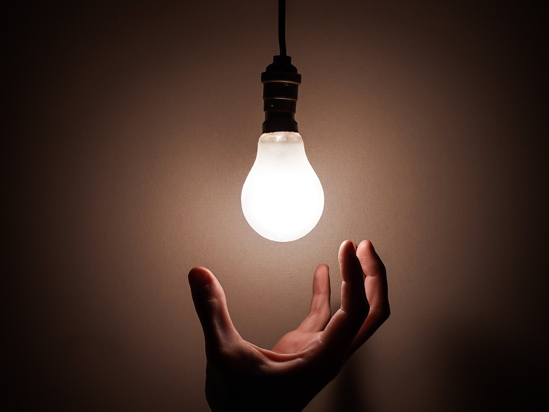 Hand turning on light bulb