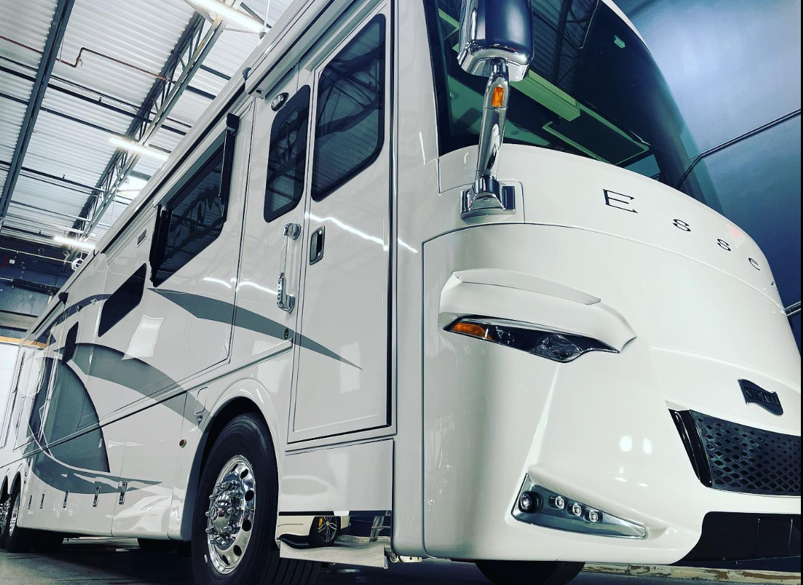 A large white rv is parked in a garage.