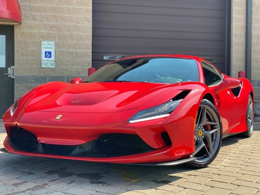 A red ferrari f8 tributo is parked in front of a building.